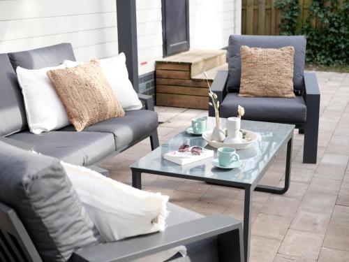 a patio with two couches and a coffee table at Welkom in het beachbos I Onthaasten op de Veluwe in Hoenderloo