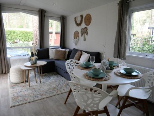 ein Wohnzimmer mit einem Tisch und einem blauen Sofa in der Unterkunft Welkom in het beachbos I Onthaasten op de Veluwe in Hoenderloo