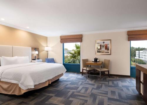 チャールストンにあるHampton Inn Charleston Northのベッド、デスク、窓が備わるホテルルームです。