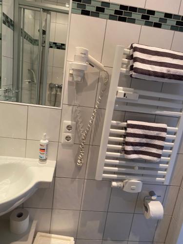 La salle de bains blanche est pourvue d'un lavabo et d'un miroir. dans l'établissement Haus Bielefeld Zimmer 30a, à Norderney
