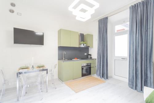 a kitchen with green cabinets and a table with chairs at Cernobbio Dream Suites by Rent All Como in Cernobbio
