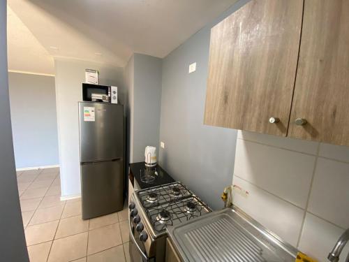 a kitchen with a stove and a refrigerator at Departamento Portal Tutuquen in Curicó