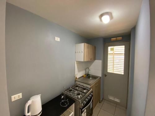 a small kitchen with a stove and a sink at Departamento Portal Tutuquen in Curicó