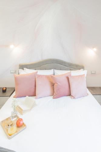 a white bed with pink pillows and a tray of fruit at Cernobbio Dream Suites by Rent All Como in Cernobbio