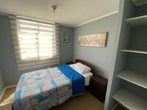 ein kleines Schlafzimmer mit einem Bett und einem Fenster in der Unterkunft Departamento Portal Tutuquen in Curicó