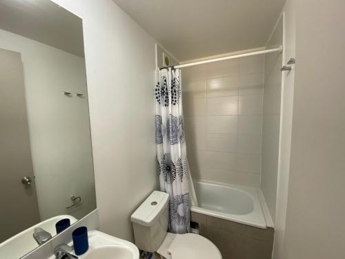 a bathroom with a toilet and a sink and a tub at Departamento Portal Tutuquen in Curicó