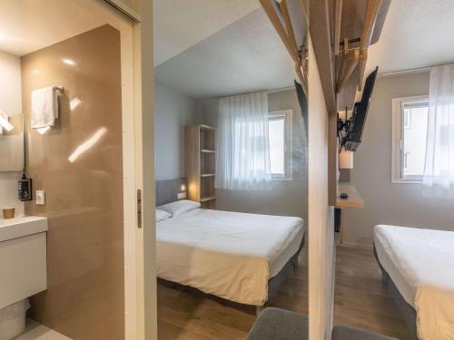 a room with two beds and a bathroom with a sink at ibis budget Ciboure St-Jean-Luz in Ciboure