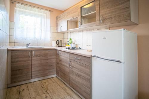 a kitchen with wooden cabinets and a white refrigerator at 4 Pory Roku in Polańczyk