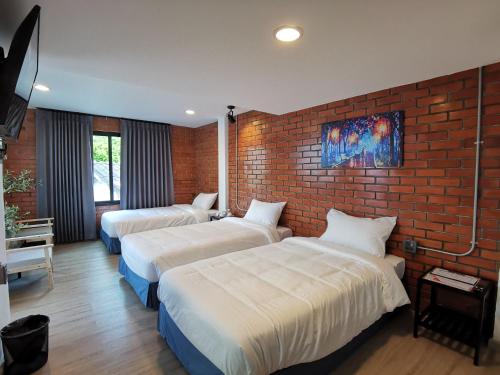 two beds in a room with a brick wall at BETONG HELLO GUESTHOUSE in Betong