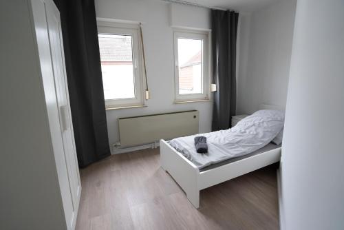 a small bedroom with a bed and two windows at Mieterlux Frankfurt Obertshausen in Obertshausen