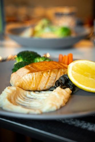 a plate of food with fish and vegetables and a lemon at Rose Rayhaan by Rotana - Dubai in Dubai