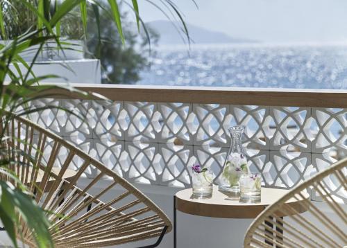 a table with two vases on a balcony with the ocean at Afroditi Venus Beach Resort in Kamari