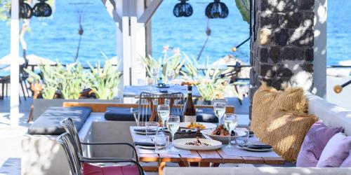 a table with plates of food and wine glasses at Afroditi Venus Beach Resort in Kamari