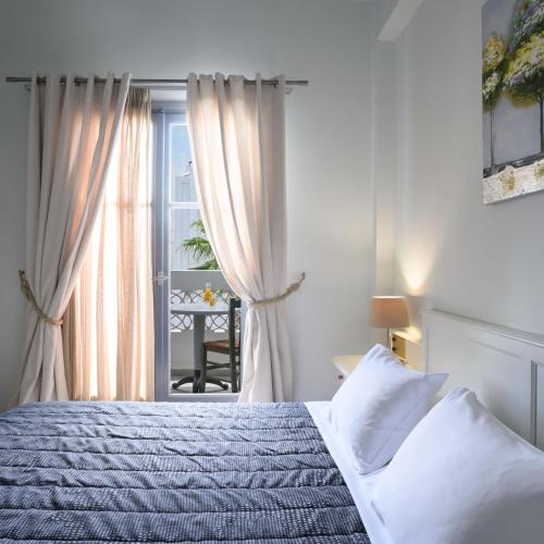 a white bedroom with a bed and a window at Afroditi Venus Beach Resort in Kamari