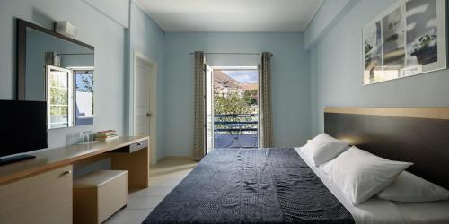 a bedroom with a bed and a tv and a window at Afroditi Venus Beach Resort in Kamari