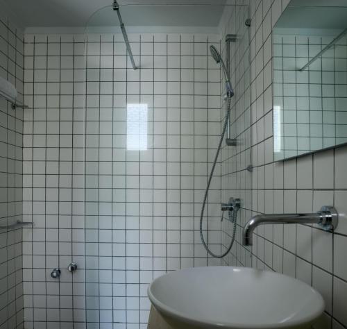 a white tiled bathroom with a shower and a toilet at Afroditi Venus Beach Resort in Kamari