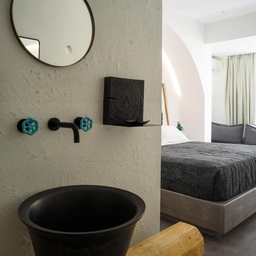 a bathroom with a black bath tub next to a bed at Afroditi Venus Beach Resort in Kamari