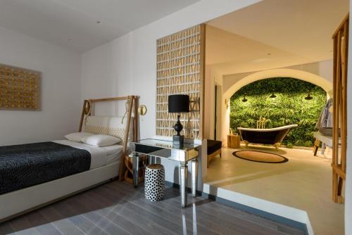 a bedroom with a bed and a bathroom with a tub at Afroditi Venus Beach Resort in Kamari