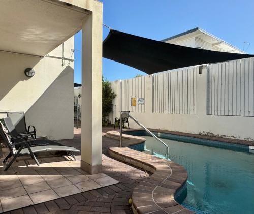 a patio with a pool and a table and a chair at Townsville Beachfront Apartment on the Strand - 2 in Townsville