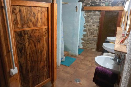 een badkamer met een houten deur en een wastafel bij Albergue del Oso TierraLuz in Arbúcies