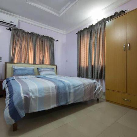 a bedroom with a bed and a large window at Sidney Apartment in Ilorin