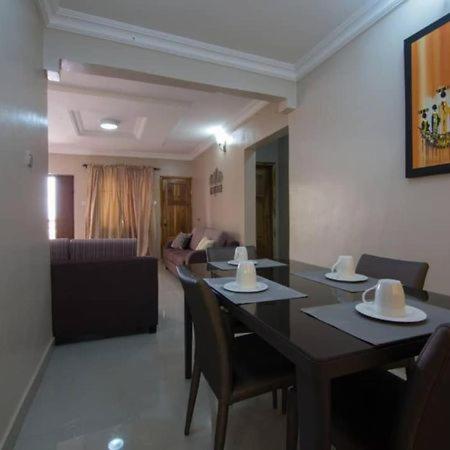 a dining room with a table and chairs and a couch at Sidney Apartment in Ilorin