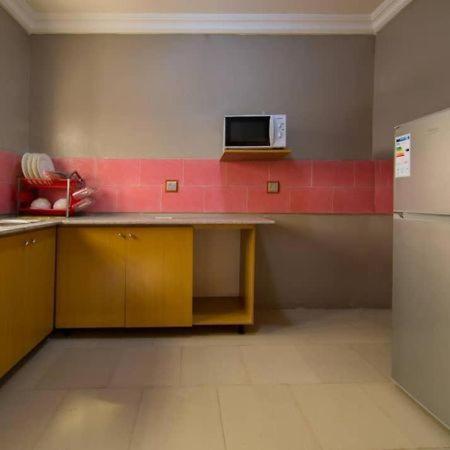 a kitchen with a counter with a microwave and a refrigerator at Sidney Apartment in Ilorin