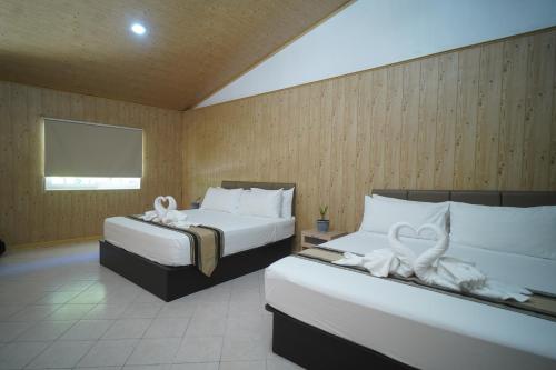 a bedroom with two beds with white towels on them at Forest Crest Nature Hotel and Resort Powered by ASTON in Nasugbu