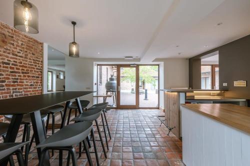 a kitchen with a bar with chairs and a brick wall at Charming Roger's Farm in Kortrijk