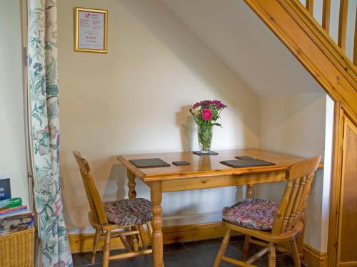 a table and two chairs with a vase of flowers on it at Glascoed Coach House Whitland in Whitland