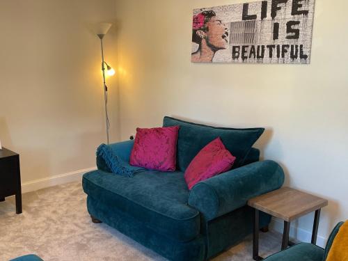 a living room with a blue couch with pink pillows at Peak View - Modern Cottage in Buxton
