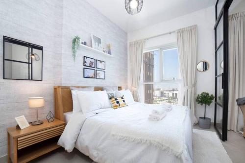 a white bedroom with a large bed and a window at Dubai Hills Collective Tower 2 in Dubai