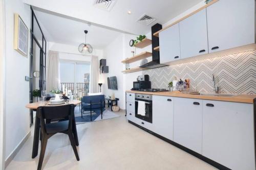 a kitchen with white cabinets and a table and a dining room at Dubai Hills Collective Tower 2 in Dubai