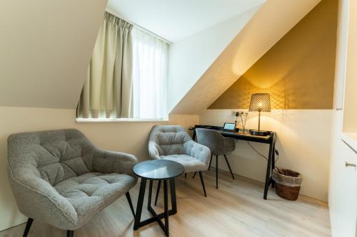 a living room with two chairs and a desk at Hotel Acacia in Bruges