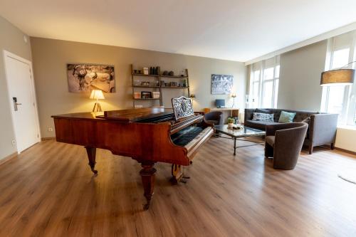 a living room with a piano and a couch at Hotel Acacia in Bruges