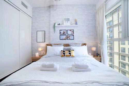 a bedroom with a large white bed with two pillows at Dubai Hills Collective Tower 2 in Dubai