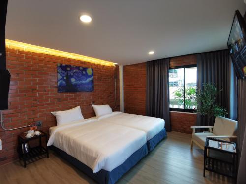 1 dormitorio con 1 cama grande y pared de ladrillo en BETONG HELLO GUESTHOUSE, en Betong