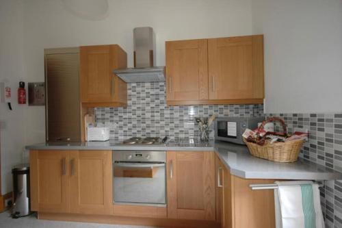a kitchen with wooden cabinets and a stove top oven at Lovely 2 bed flat located next to Edinburgh Castle in Edinburgh