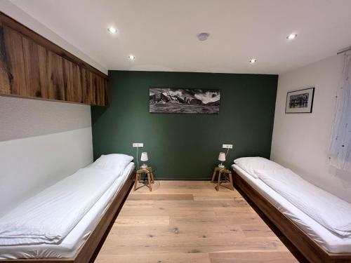 a room with two beds and a green wall at Moderne Wohnung mit Ausblick in Niedernhall