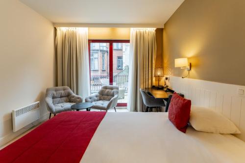 ブルージュにあるホテル アカシアの大きなベッドと椅子2脚が備わるホテルルームです。