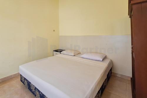 a small bedroom with a white bed with two pillows at Aman Guest House Redpartner in Palangkaraya