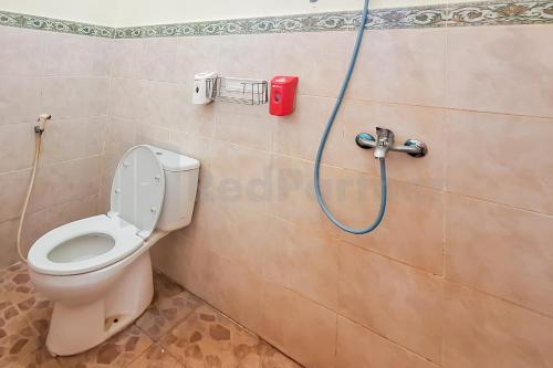 a bathroom with a toilet with a hose on the wall at Aman Guest House Redpartner in Palangkaraya
