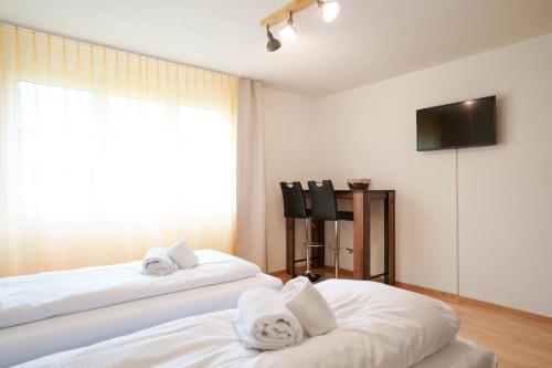 two white beds in a room with a television at Haus Gmür Amden Obergeschoss in Amden
