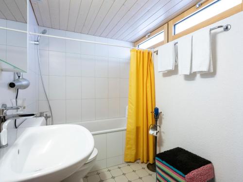 uma casa de banho com um WC branco e uma cortina de chuveiro amarela. em Ferienhaus Casa Chapf em Amden