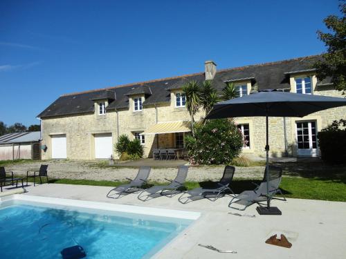 une piscine avec des chaises et un parasol ainsi qu'une maison dans l'établissement Les Petites Landes - Piscine privée proche plages, à Cricqueville-en-Bessin