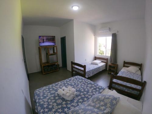 a small room with two beds and a window at Pousada Silvestre in Tramandaí