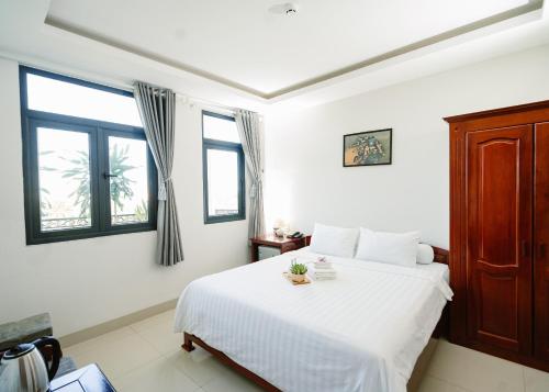 a bedroom with a white bed and two windows at NAM CẦN THƠ HOTEL in Ấp Phú Thạnh (4)
