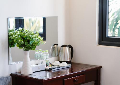 a table with a vase of flowers and a mirror at NAM CẦN THƠ HOTEL in Ấp Phú Thạnh (4)