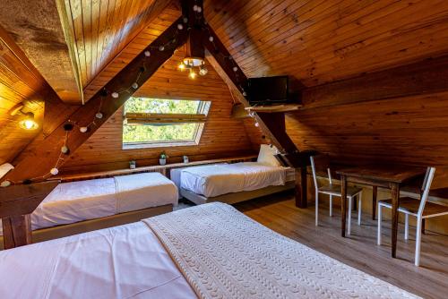 a room with two beds and a table in a cabin at Auberge de la Rivière in Foncine-le-Haut