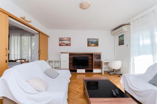 a living room with white furniture and a tv at Apartments Zdenka in Lopar